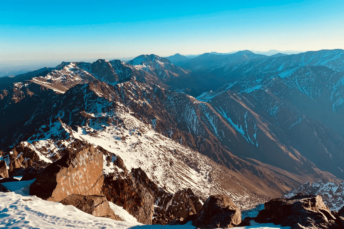 Snow-covered peaks of the High Atlas Mountains under a clear blue sky in Morocco.