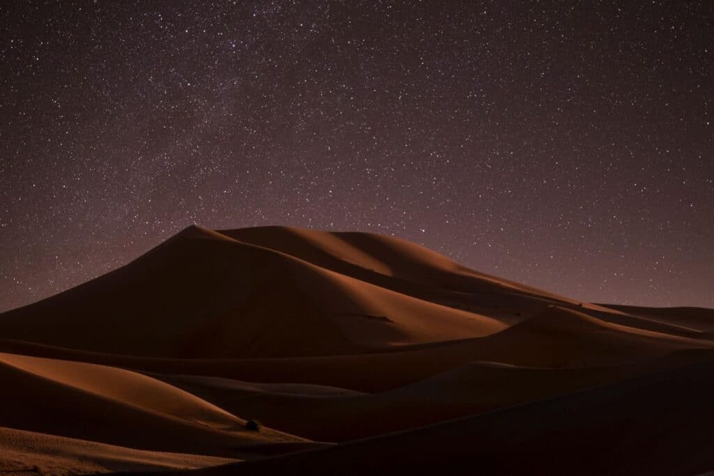 Starry night sky over sand dunes in the Moroccan Sahara, capturing the tranquility and beauty of the desert landscape in Merzouga or Zagora.